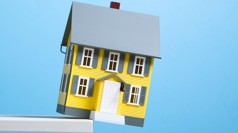 A model house teetering on the edge of a table